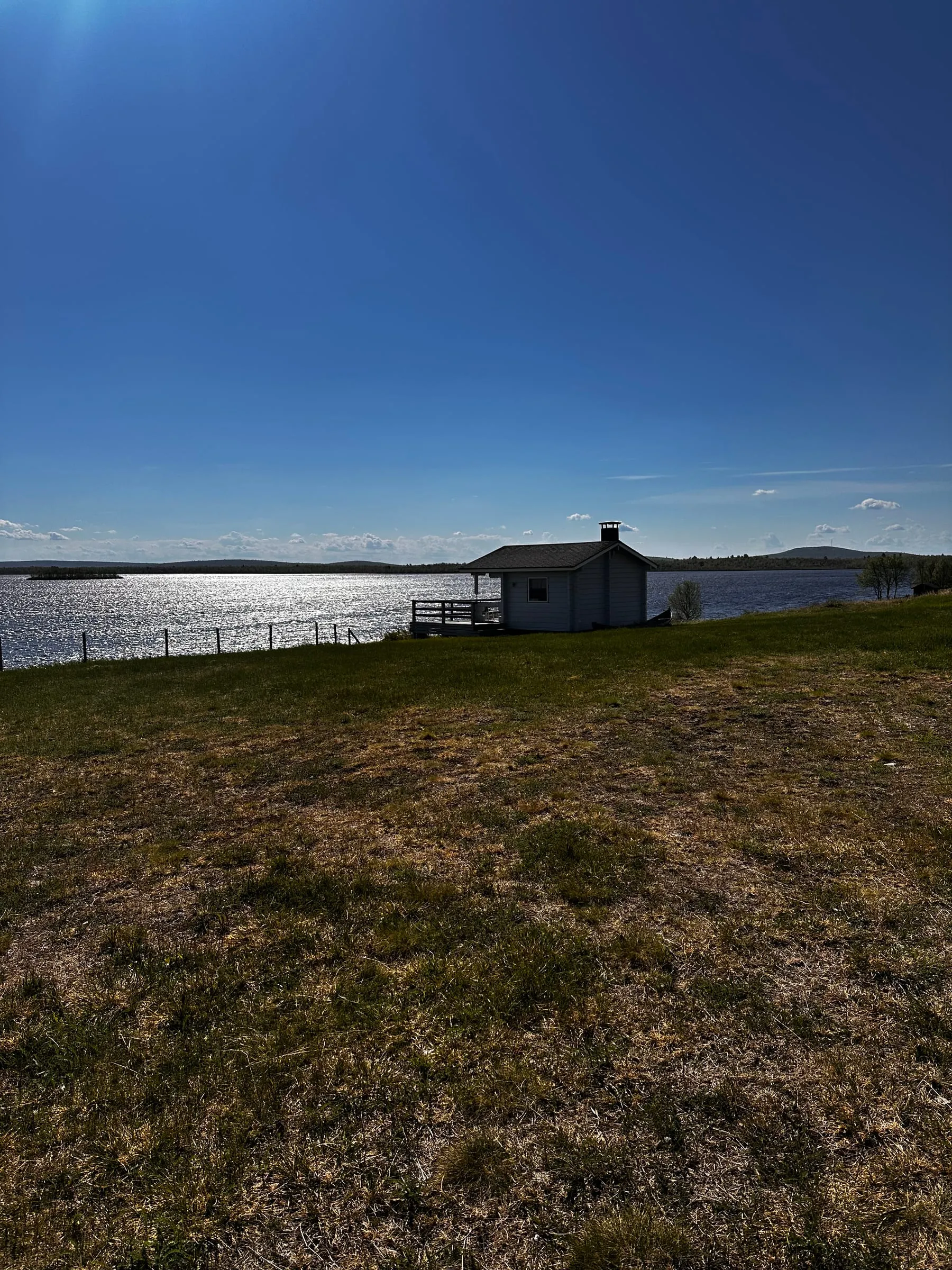 Mökki ja sauna järven rannassa seesteisessä iltavalossa